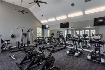 A gym with cardio machines and other exercise equipment and a flat screen tv